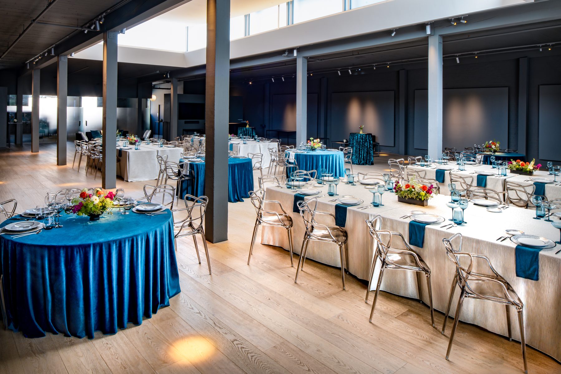 Palladian Arthouse flagship 5,000 sq ft hall set for a wedding reception with blue velvet tables and ghost chairs